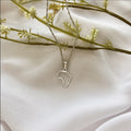 Silver necklace with an Africa outline pendant on a white fabric background